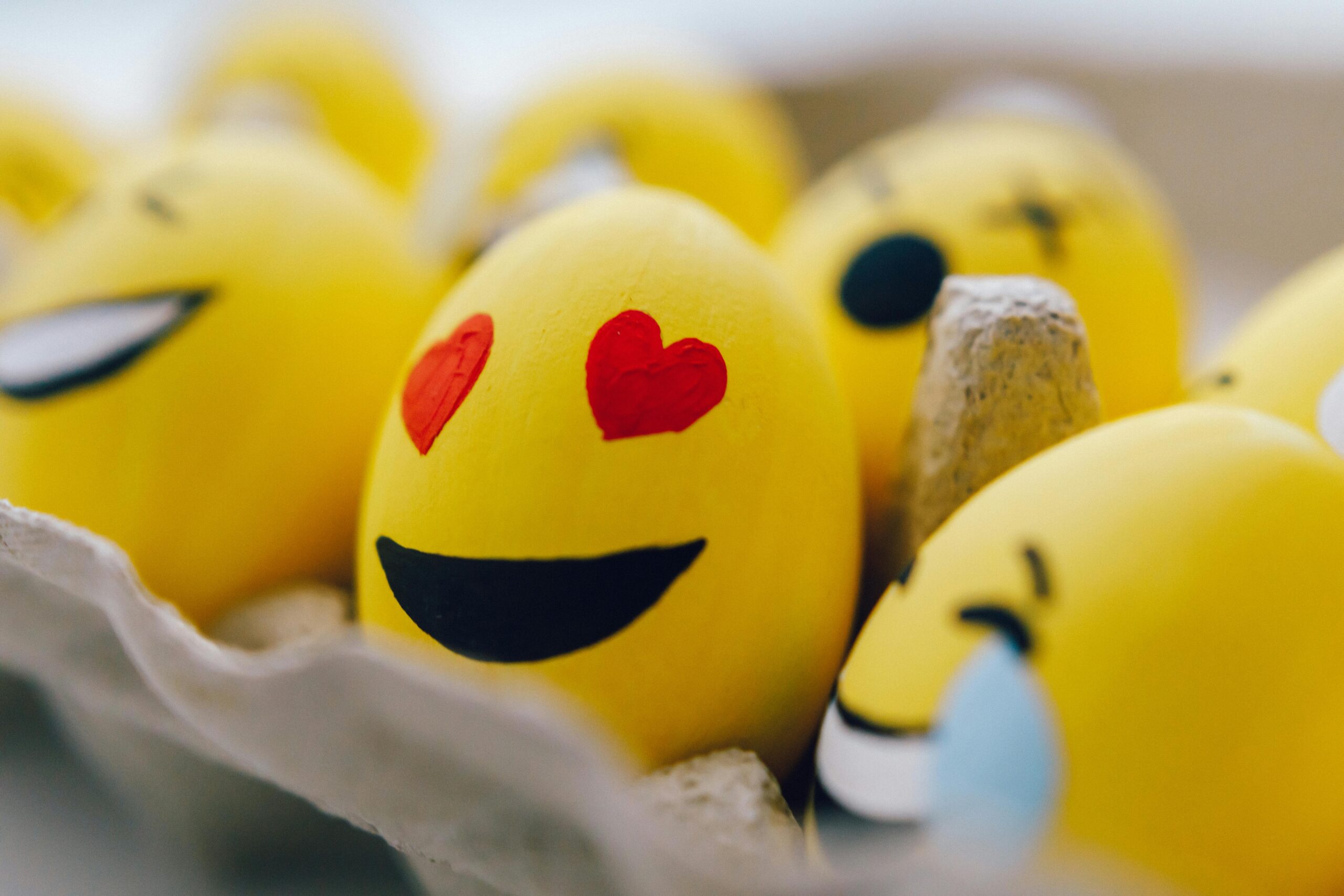 Bright yellow emoji Easter eggs with fun expressions in an egg carton. Perfect for festive decorations.